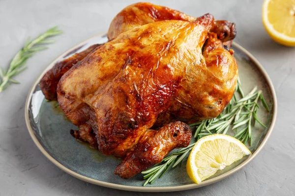 Ev yapımı limon ve Herb Rotisserie Tavuk Gri arka planda bir tabakta, yan manzara. 