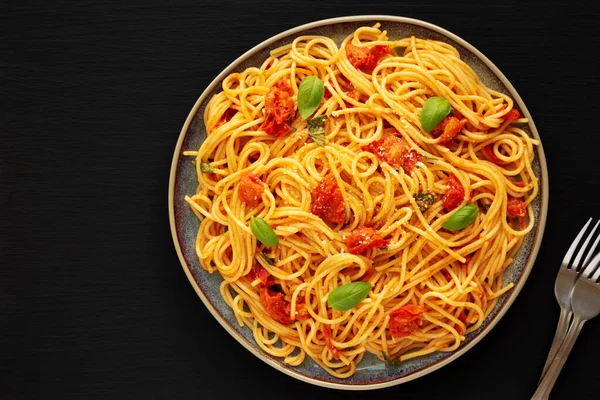 Siyah bir tabakta taze domates soslu ev yapımı spagetti makarna, üst manzara. Dümdüz, tepeden, yukarıdan. Boşluğu kopyala.