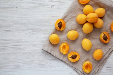 Raw White Apricot Angelcots on a white wooden surface, top view. Flat lay, overhead, from above. Space for text.