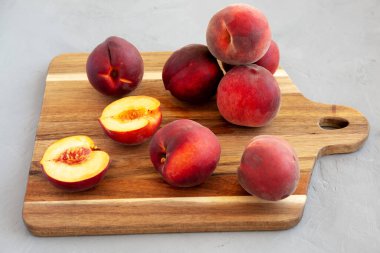 Raw Organic Yellow Peaches on a wooden board, side view.