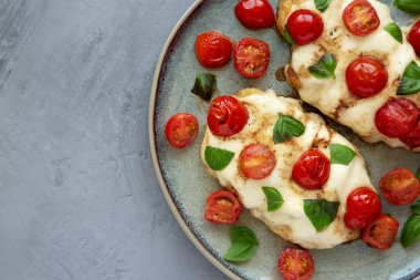 Homemade Caprese Chicken Parmesan with tomato, mozzarella and basil on a Plate, top view. Space for text.