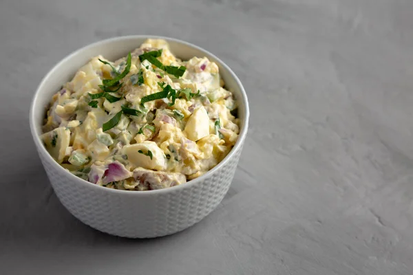 Homemade Healthy Potato Salad with Eggs in a Bowl on a gray background, side view. Space for text.