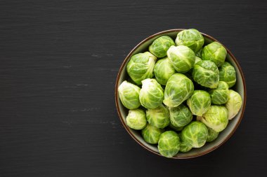 Raw Organic Brussel Sprouts in a Bowl on a black background, top view. Flat lay, overhead, from above. Space for text.