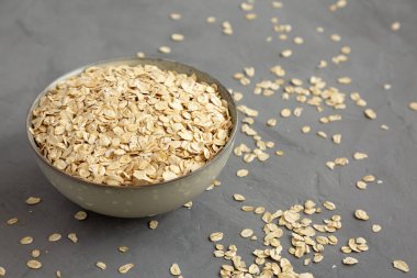 Dry Organic Rolled Oats in a Bowl on a gray background, low angle view. 