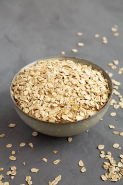Dry Organic Rolled Oats in a Bowl on a gray background, side view. 