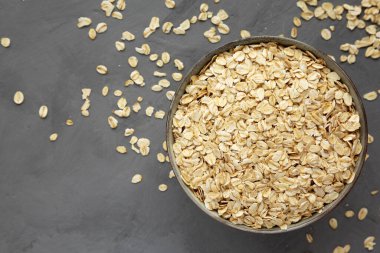 Dry Organic Rolled Oats in a Bowl on a gray background, top view. Flat lay, overhead, from above.