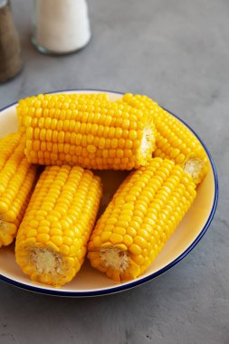 Homemade Steamed Corn on the Cob with Butter on a Plate, side view. 
