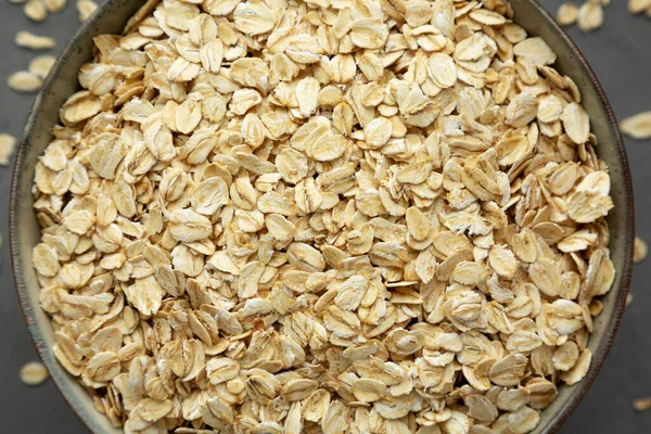 Dry Organic Rolled Oats in a Bowl on a gray surface, top view. Flat lay, overhead, from above.