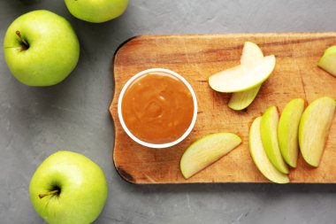 Ev yapımı karamelli elma sosu, ahşap bir tahta üzerinde, üst manzara. Dümdüz, tepeden, yukarıdan.