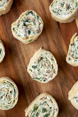 Domuz pastırması, ıspanak, yeşil soğan ve krem peynirli ev yapımı fırıldak tortilla aperatifleri. Dümdüz, tepeden, yukarıdan. 