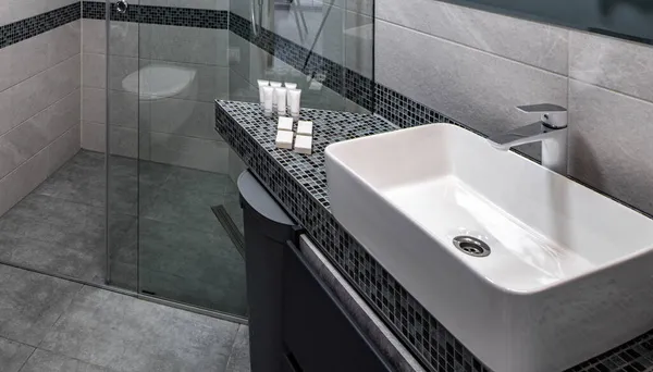 Modernes Interieur des Badezimmers in einer modernen Wohnung. Graue Farben. Weißes Waschbecken. Glasduschkabine. — Stockfoto