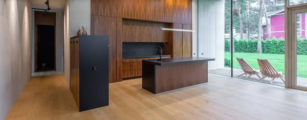 Lüks özel evdeki ahşap mutfağın modern iç mimarisi. Bahçe görünümü.