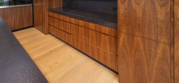 Interior modern dari dapur kayu dengan counter hitam. Laminate lantai. — Stok Foto