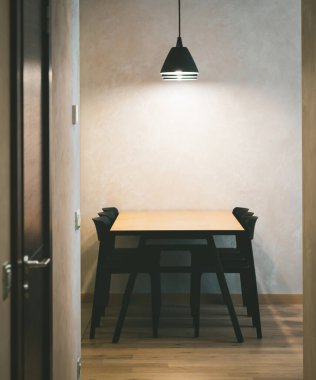 Modern iç mekan. Ahşap masanın altında siyah lambalar ve siyah sandalyeler..