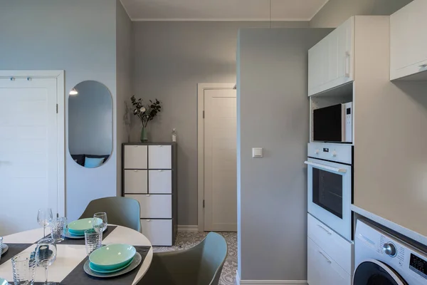 Interior kontemporer dari apartemen modern. Dapur dengan peralatan. Meja makan malam. Mesin cuci. — Stok Foto