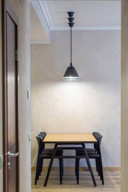 Modern iç mekan. Ahşap masanın altında siyah lambalar ve siyah sandalyeler..
