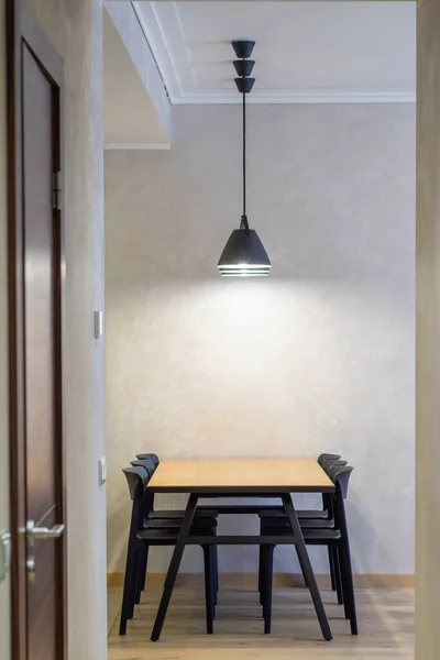 Interior moderno. Lâmpadas pretas sob mesa de madeira e cadeiras pretas. — Fotografia de Stock