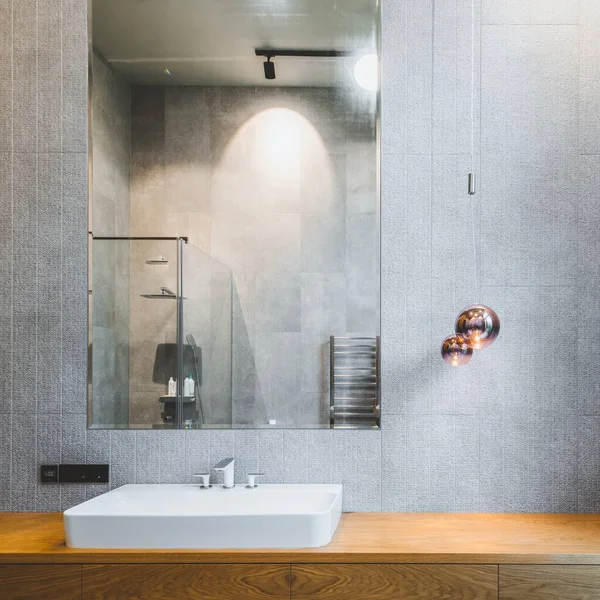 Interno del bagno in appartamento di lusso. Design grigio e legno. Lavello bianco. — Foto Stock