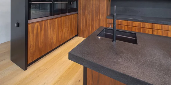 Современный интерьер деревянной кухни с раковиной и черным счетчиком. — стоковое фото