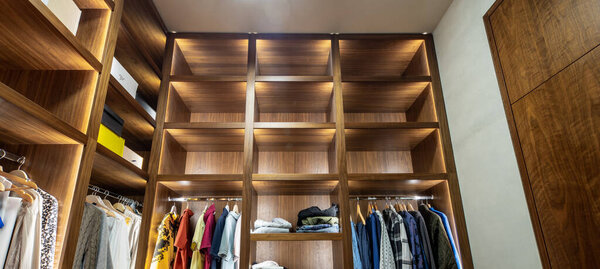 Modern interior of dressing room in luxury apartment. Wooden shelves