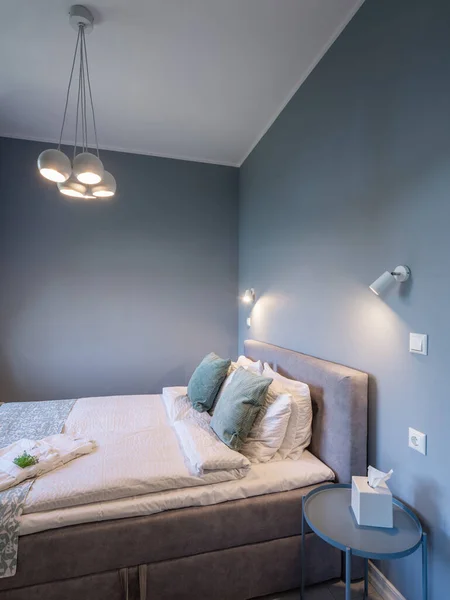 Lüks bir dairede yatak odasının modern iç mekanı. Gri renkler. Peçeteler komodinin üzerinde. Sıcak yatak.. — Stok fotoğraf