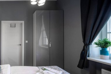 Gri renkli yatak odasının çağdaş iç mekanı. Modern daire. Pervazda çiçek var. Beyaz kapı. Dolap.