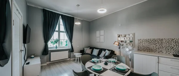 Modern interieur van studio appartement in grijze kleuren. Woonkamer met gezellige bank. Eettafel gedekt.. — Stockfoto