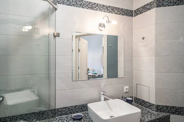 Modernes Interieur des Badezimmers in einer Luxuswohnung. Dusche aus Glas vorhanden. Weißes Waschbecken. Graue Fliese. — Stockfoto