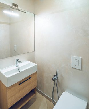 Banyo 'nun modern iç mekanı. Ahşap çekmeceli ve aynalı beyaz lavabo. Tuvalet..