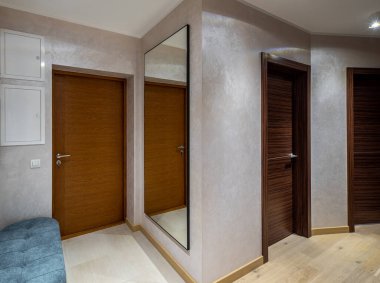 Lüks apartmandaki modern salon. Tahta giriş kapısı. Mavi kadife kanepe. Ayna duvarda.