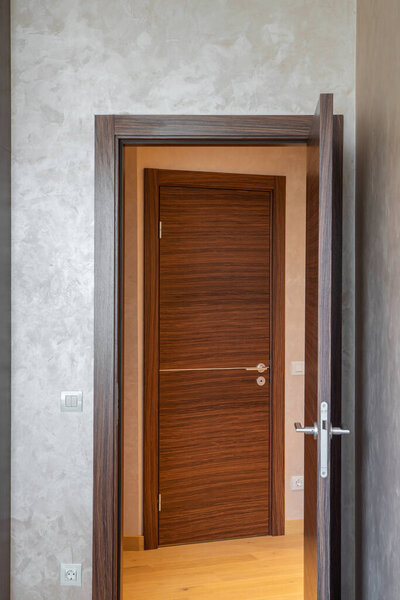 Opened wooden door from room to hall. Modern interiro of apartment.