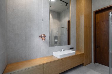 Lüks dairede modern banyo. Gri ve ahşap dizayn. Beyaz lavabo ve ayna.