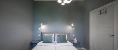 Gri tonlarda modern yatak odası. Lüks daire. Büyük boy yatağın ön görüntüsü.