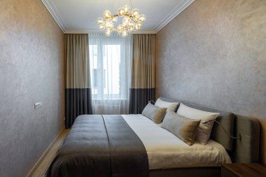 Konforlu yatak odasının modern iç mekanı dairede. Kahverengi renkli. Büyük boy yatağın yan görünümü.