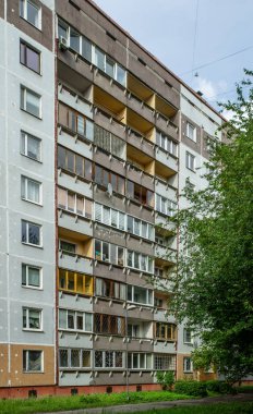 Riga, Letonya 'da çok katlı bir bina ön cephesi. Tipik Sovyet sonrası şehir mimarisi. Bahçedeki yeşil ağaç.
