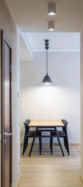 Modern iç mekan. Ahşap masanın altında siyah lambalar ve siyah sandalyeler. Koridordan görüntüle.