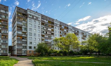 Riga, Letonya 'da çok katlı bir bina ön cephesi. Tipik Sovyet sonrası şehir mimarisi. Bahçedeki yeşil ağaç.