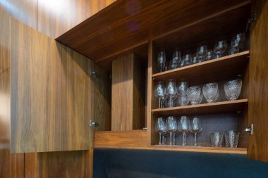 Lüks dairenin modern iç mimarisi. Şık ahşap mutfak. Dolap açıldı. Raflarda bardaklar.