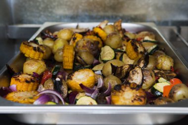 Izgara mısır, soğan, mantar, kabak ve metal tabakta patates. Restoranın mutfağı..