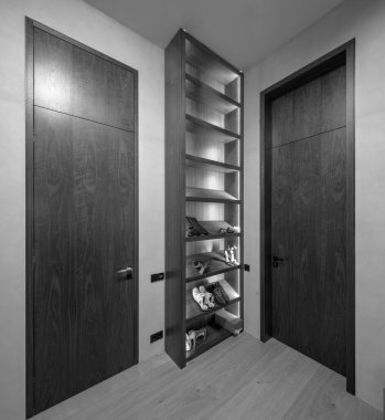 Lüks dairenin modern iç mimarisi. Ayakkabılar için aydınlatılmış raflar. Tahta kapılar. Siyah ve beyaz.