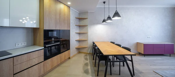アパートの広々とした光キッチンのモダンなインテリア 木造建築 テーブルと椅子 空の棚 — ストック写真