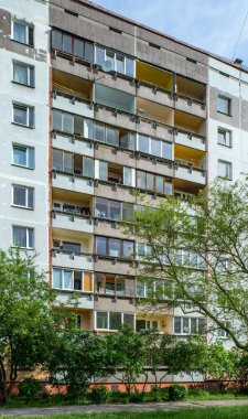 Riga, Letonya 'da çok katlı bir bina ön cephesi. Tipik Sovyet sonrası şehir mimarisi. Bahçedeki yeşil ağaç.