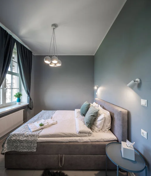 Yatak odasının gri tonlarında modern bir iç mekan. Yastıklı kraliçe yatağı. — Stok fotoğraf