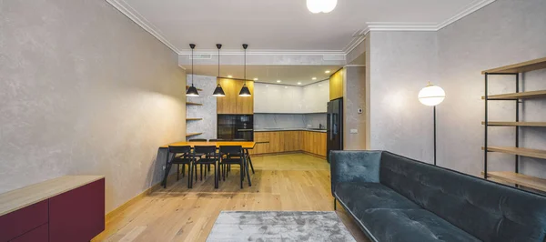 Moderní interiér studio apartmánu. Dřevěná a černá kuchyně. Sofa. — Stock fotografie