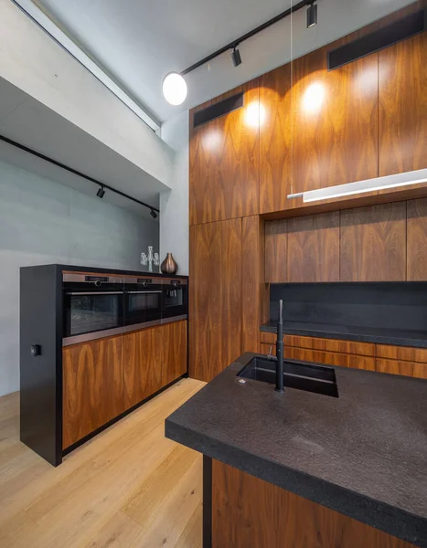 Interior moderno da cozinha de madeira com pia e contador preto. — Fotografia de Stock