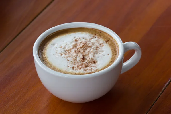 A cup of Capuchino coffee in a white cup on wooden background. — Stock Photo, Image