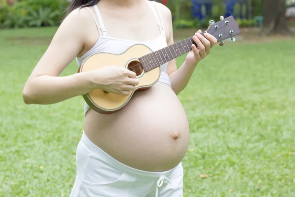 Gravida mamma spelar ukulele — Stockfoto