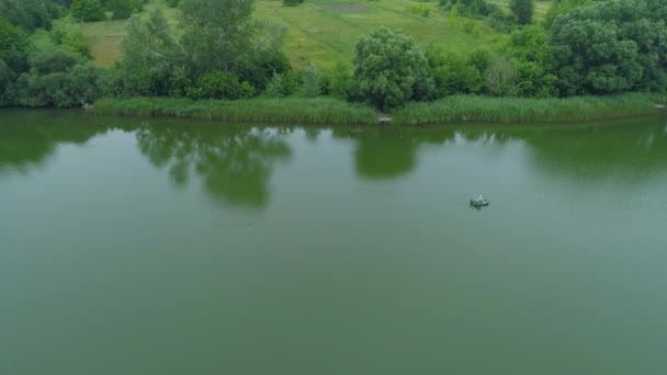 Aerial view fisherman is fishing sitting on an inflatable boat in lake — Stock Video