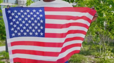 Kapalı kapılar ardında Amerikan bayrağı taşıyan Afro-Amerikan bir adam var.