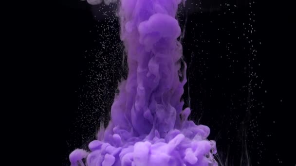 Tinta púrpura y amarilla de cámara lenta mezclándose en agua, girando suavemente bajo el agua — Vídeo de stock